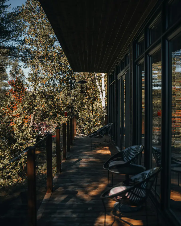 A timber walkway along glass rooms in a dark forest