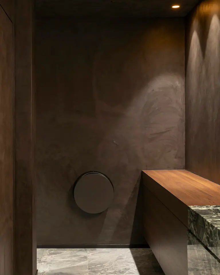 A dark bathroom of timber and stone in low warm light