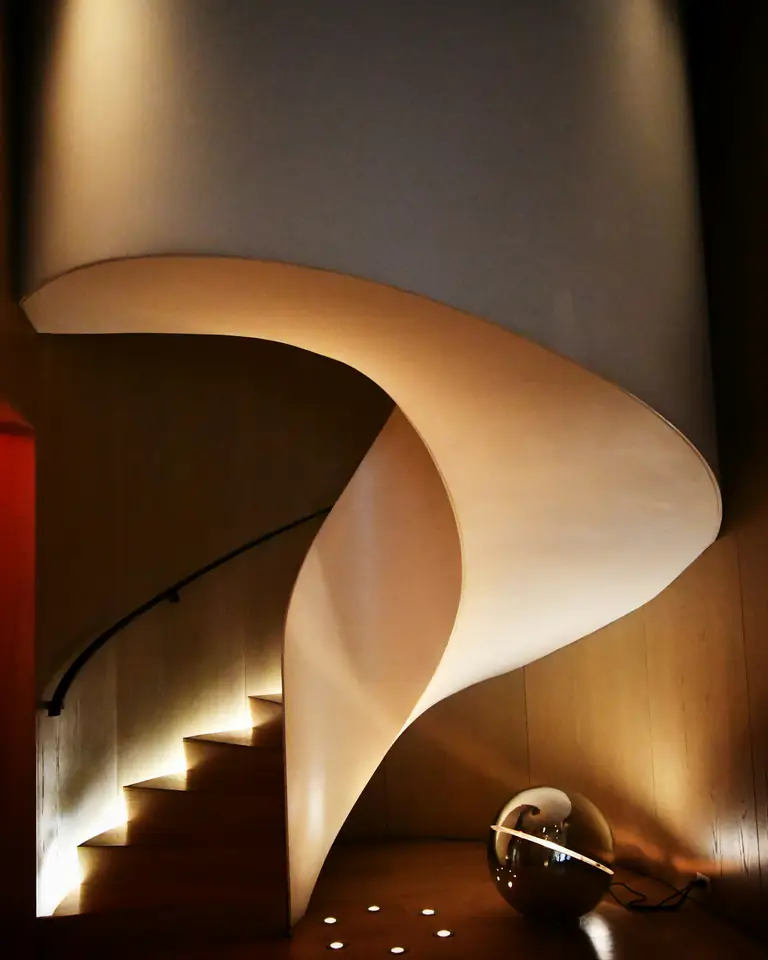 A sculptural spiral stair lit warmly from below