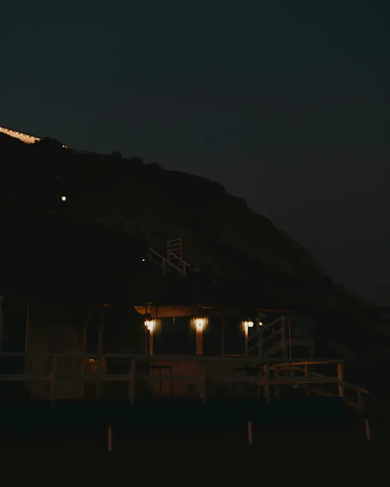 A few lit rooms low on a dark mountainside at night