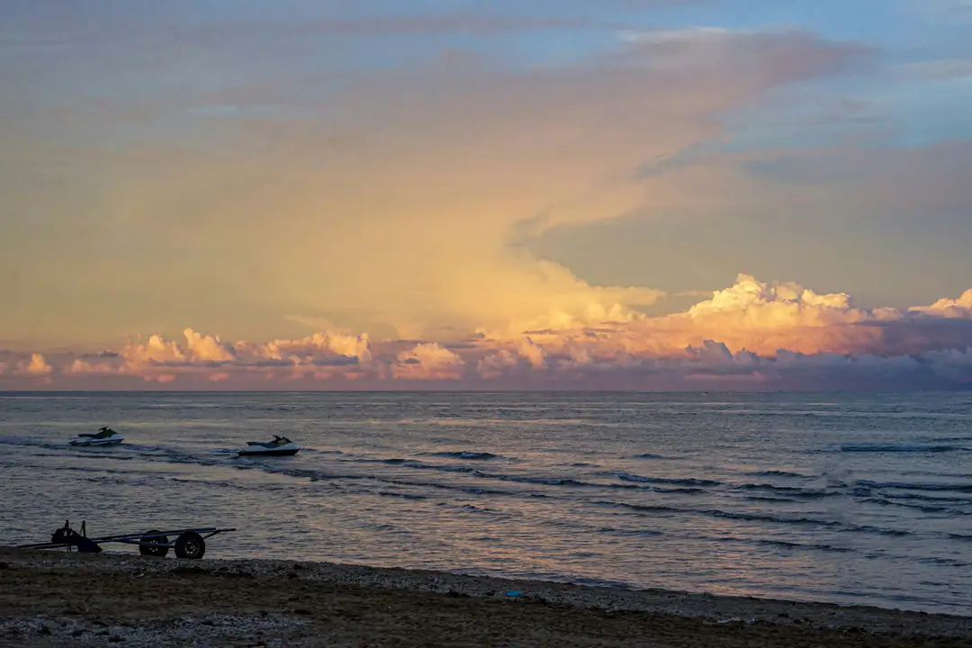Low clouds lit gold over a calm sea at sunset