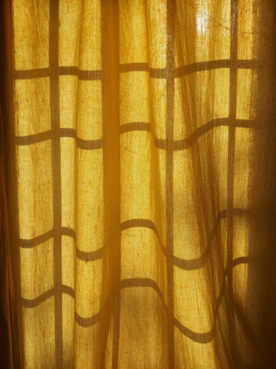 Amber light glowing through a pleated linen curtain